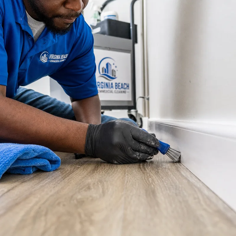 Technician detailing commercial baseboards and floor edges with appropriate tools